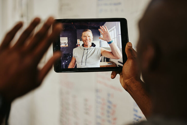 A personal trainer waving on a video call